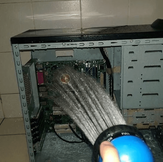 A computer being rinsed with a hose